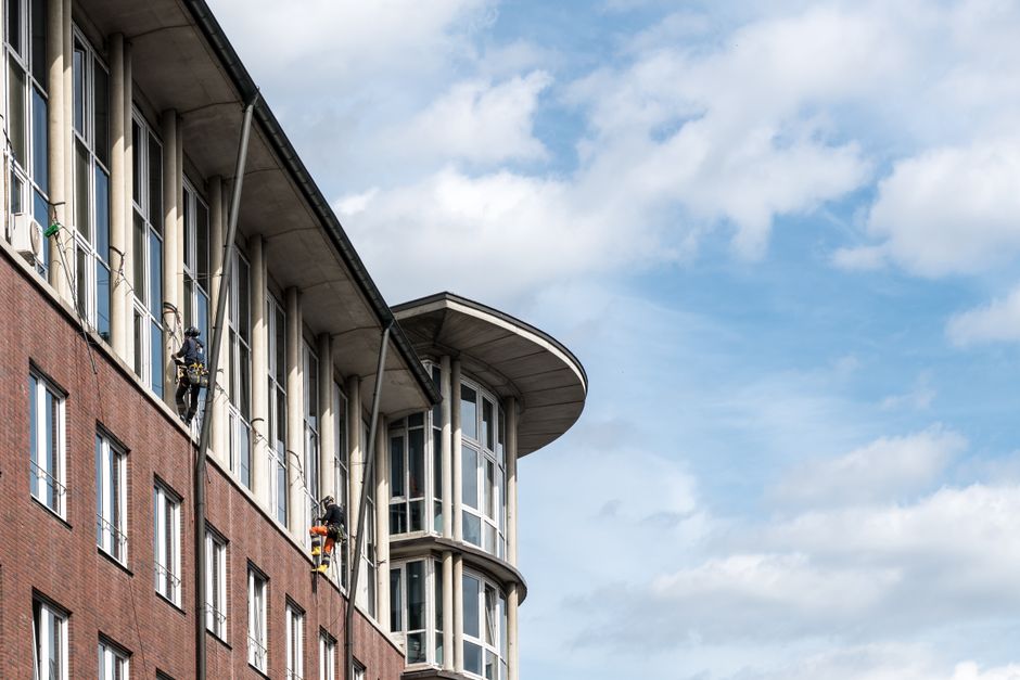 Professional window cleaners on a modern building facade in Hamburg, Germany.